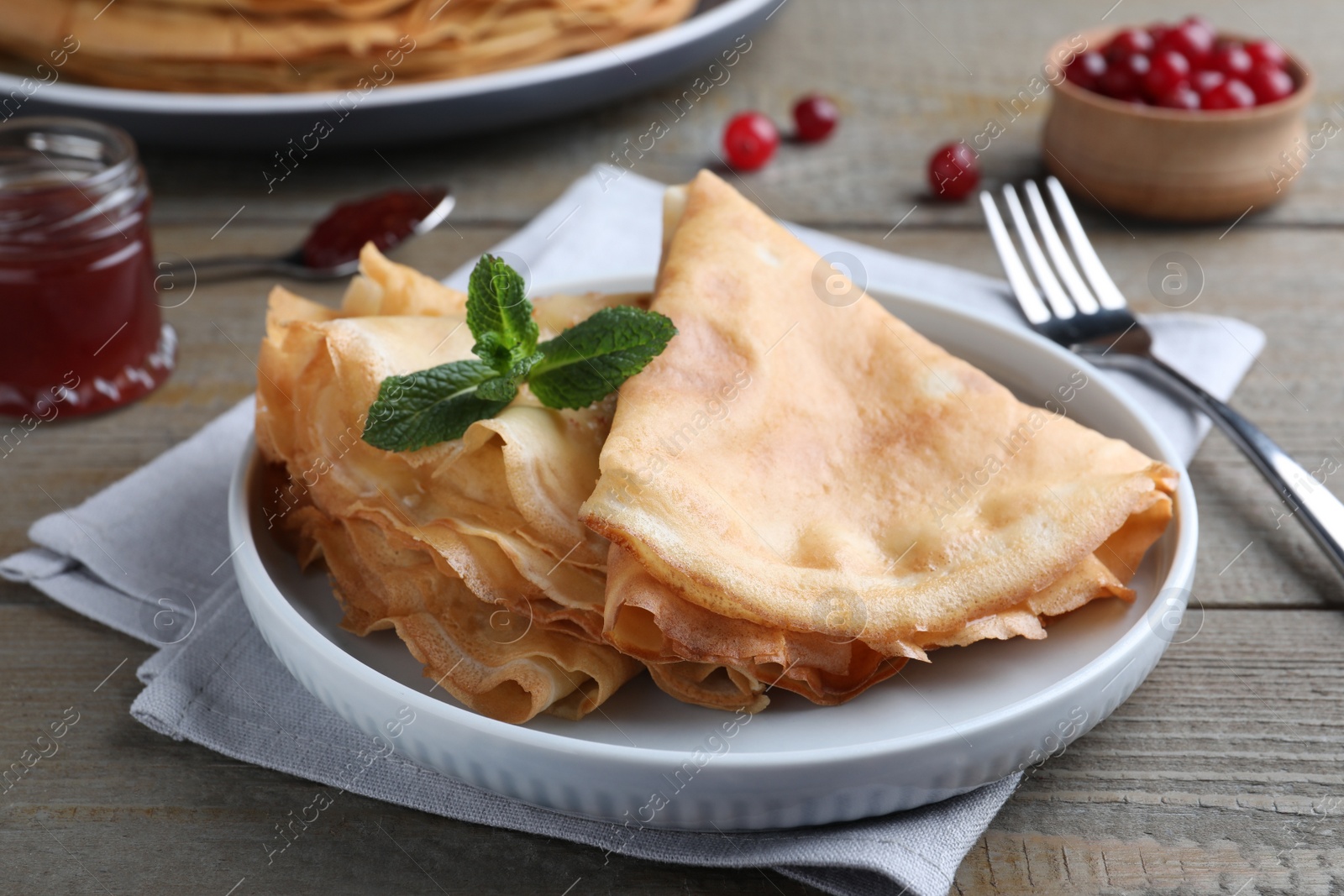 Photo of Delicious crepes served with mint on grey wooden table, closeup