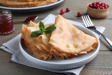 Photo of Delicious crepes served with mint on grey wooden table, closeup