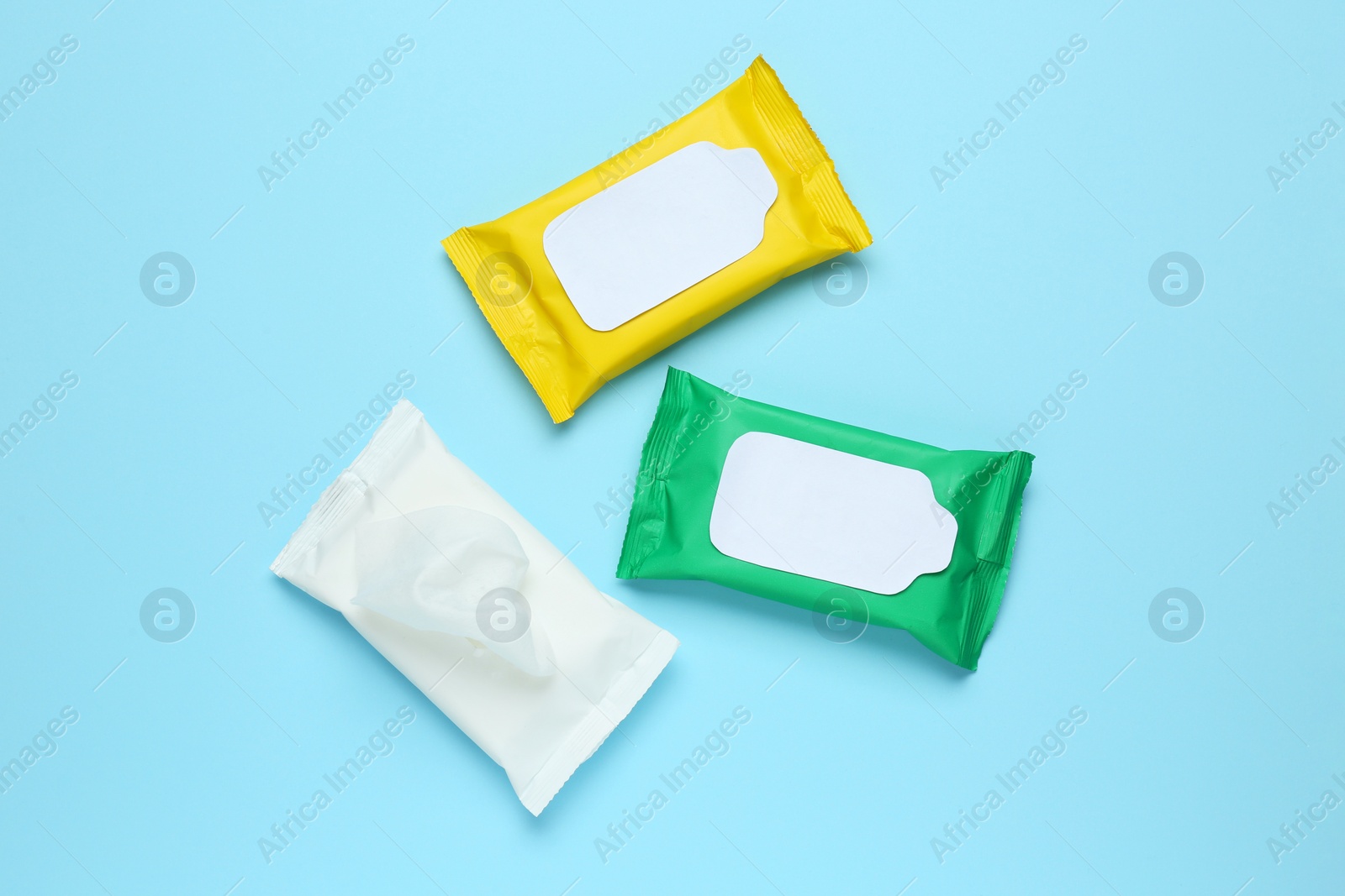 Photo of Wet wipes flow packs on light blue background, flat lay