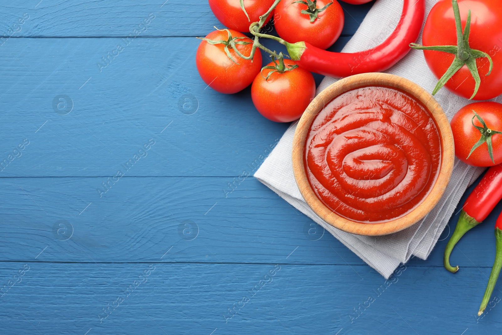 Bowl of tasty ketchup, tomatoes and peppers on blue wooden table, flat lay. Space for text Photo of Bowl of tasty ketchup, tomatoes and peppers on blue wooden table, flat lay. Space for text
