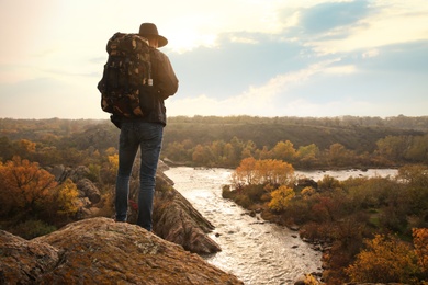 Traveler with backpack enjoying beautiful view near mountain river. Autumn vacation