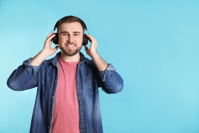 Handsome man enjoying music in headphones on color background. Space for text