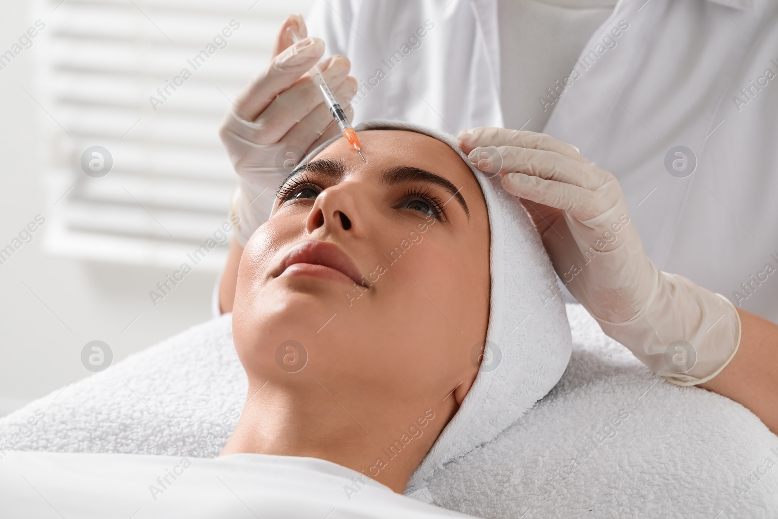 Photo of Doctor giving facial injection to young woman in clinic. Cosmetic surgery