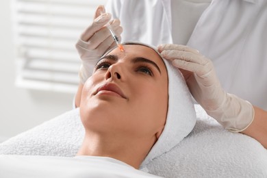 Doctor giving facial injection to young woman in clinic. Cosmetic surgery