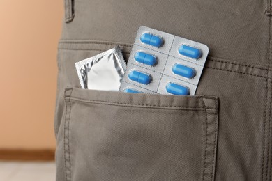 Photo of Pants with pills and condom in pocket, closeup. Potency problem