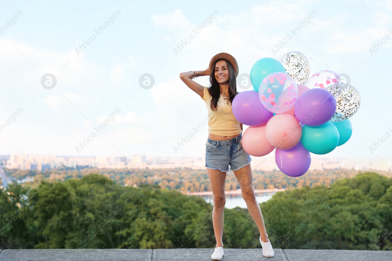 Photo of Cheerful young woman with color balloons in park