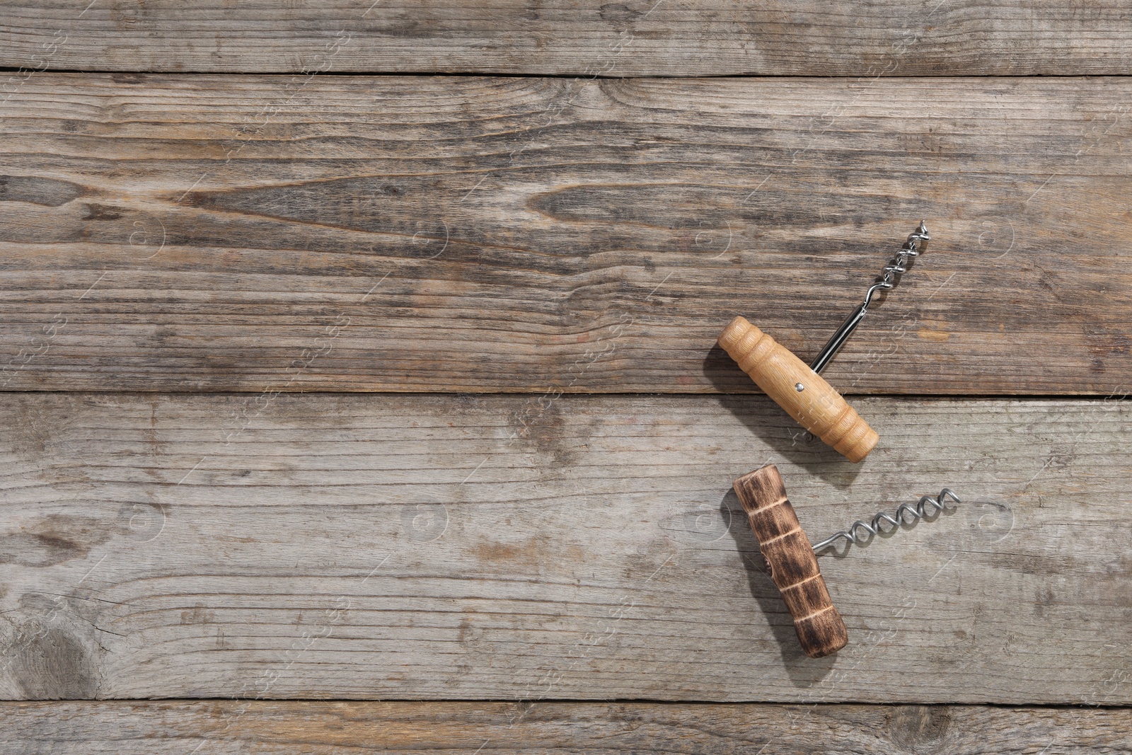 Photo of Different corkscrews on wooden table, flat lay. Space for text