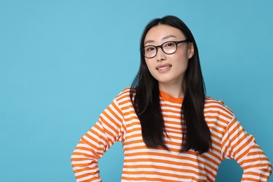 Photo of Portrait of happy woman in glasses on light blue background. Space for text