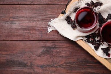 Photo of Freshly brewed hibiscus tea on wooden table, flat lay. Space for text