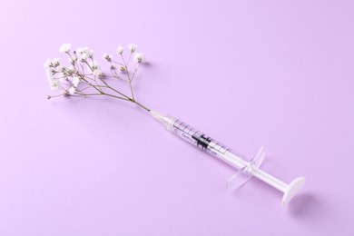 Photo of Cosmetology. Medical syringe and gypsophila on violet background