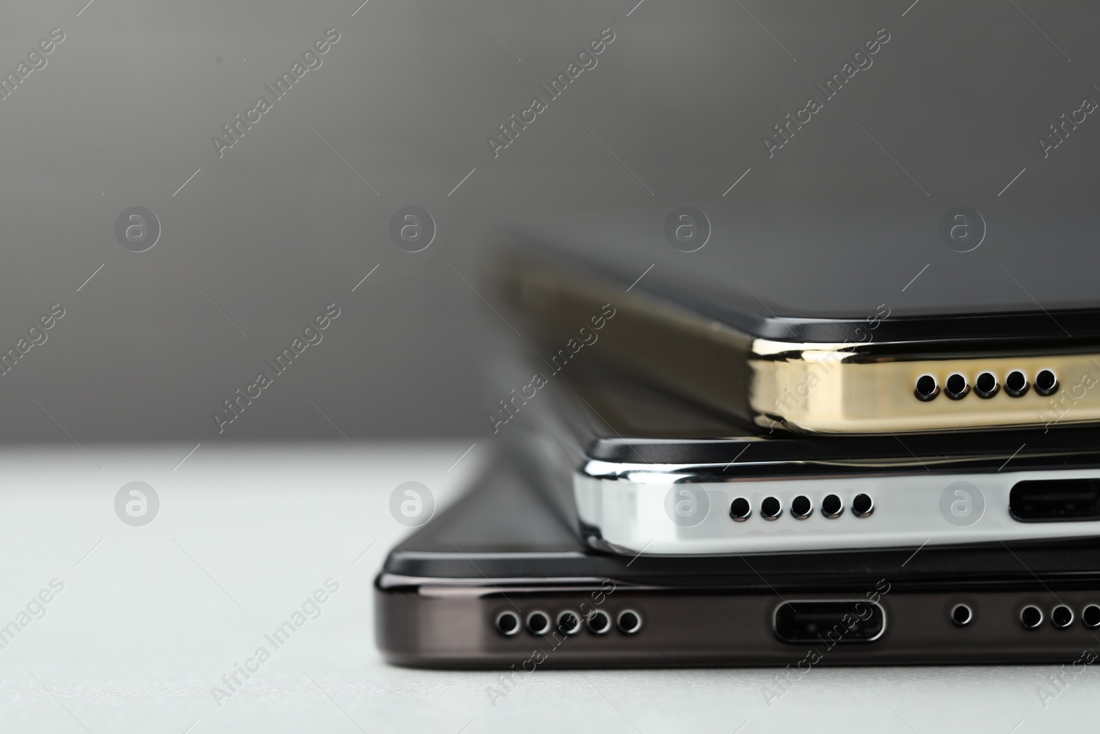 Photo of Stack of modern smartphones on white table, closeup. Space for text