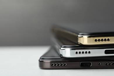 Stack of modern smartphones on white table, closeup. Space for text