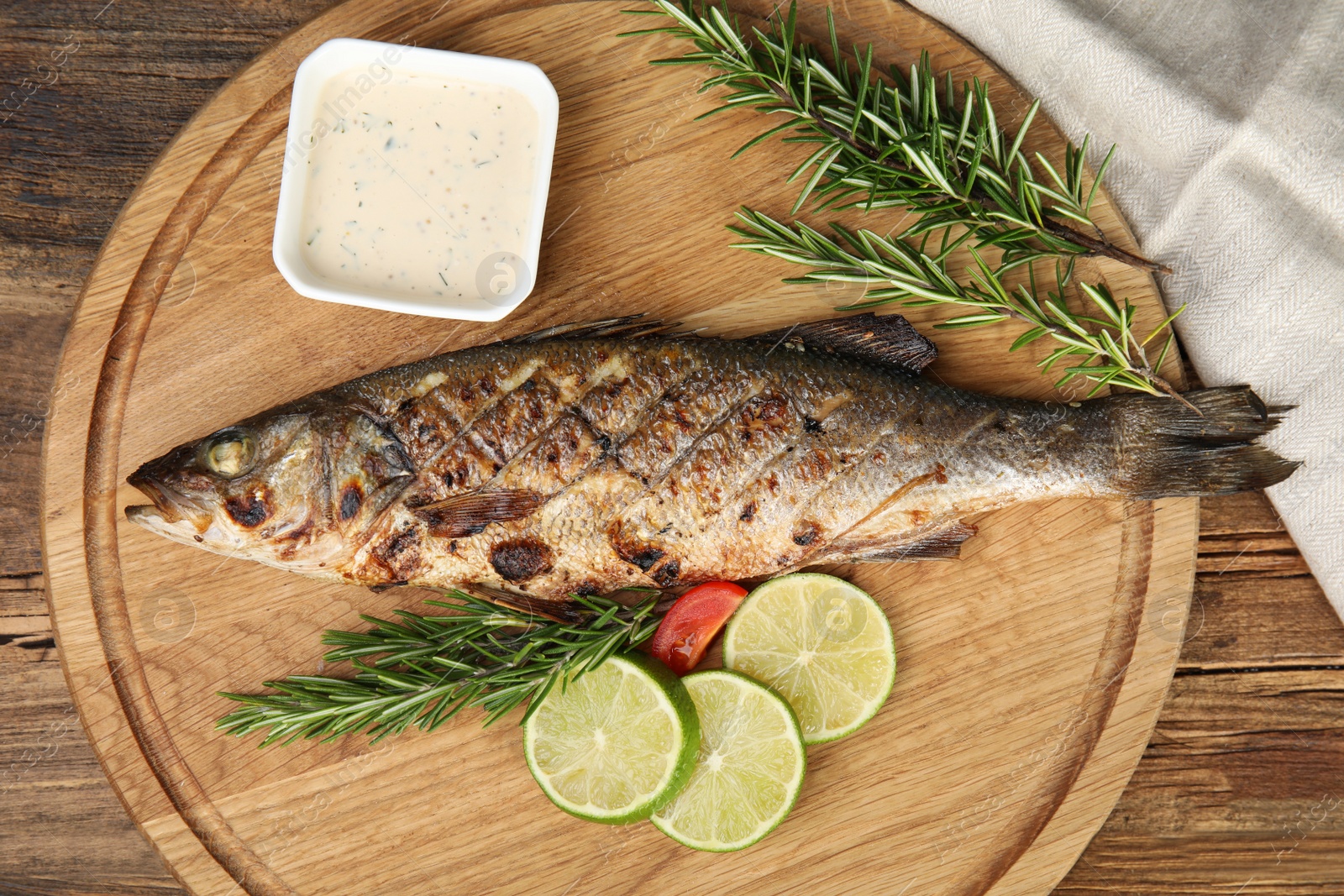 Photo of Delicious grilled fish served on wooden table, top view