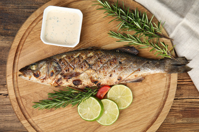 Photo of Delicious grilled fish served on wooden table, top view