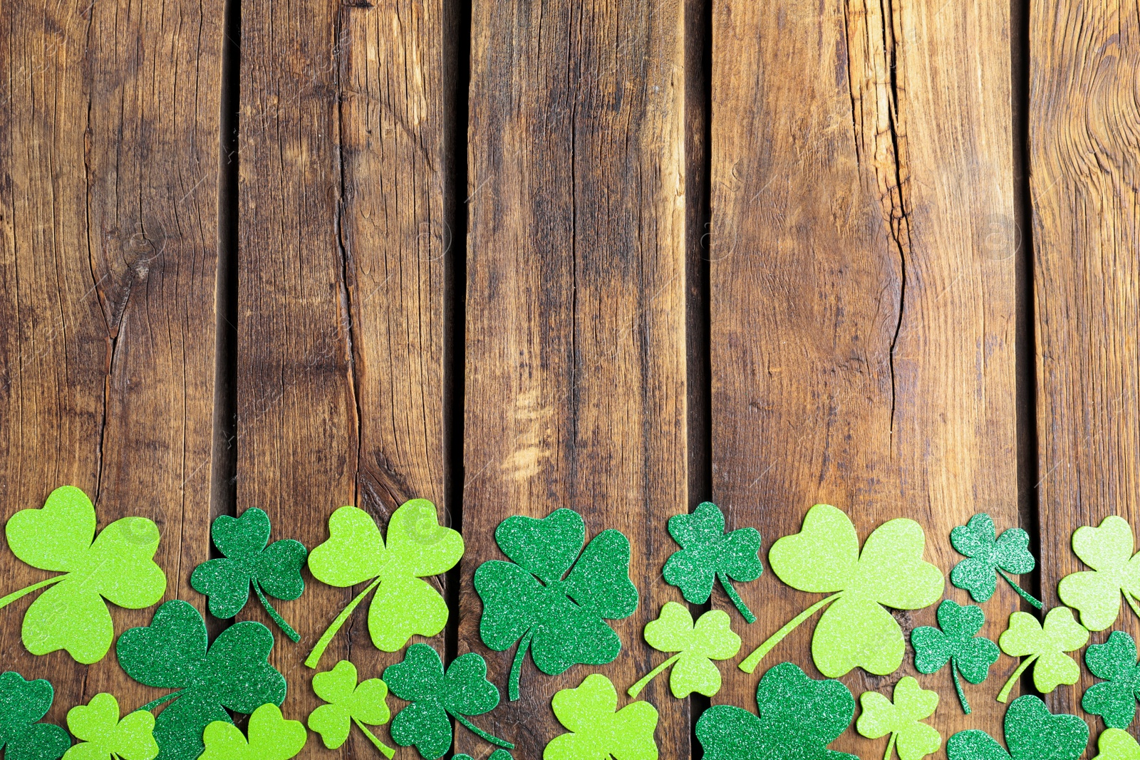 Photo of Flat lay composition with clover leaves on wooden table, space for text. St. Patrick's Day celebration