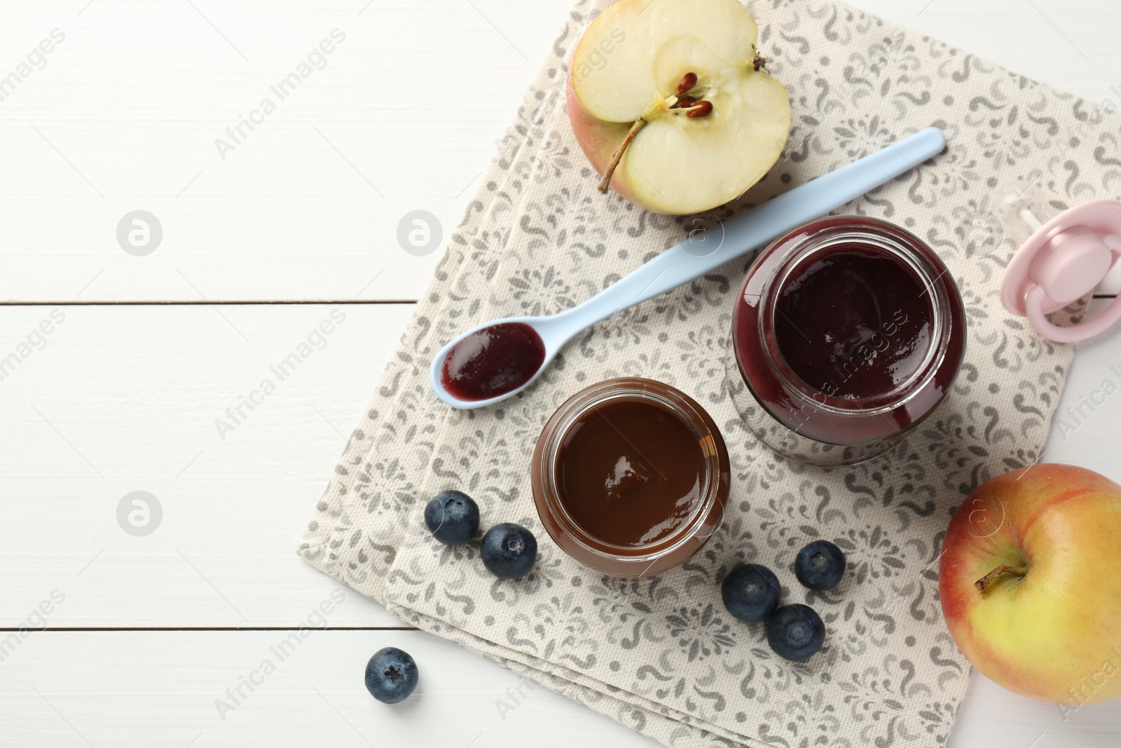 Photo of Tasty baby food in jars and ingredients on white wooden table, flat lay. Space for text