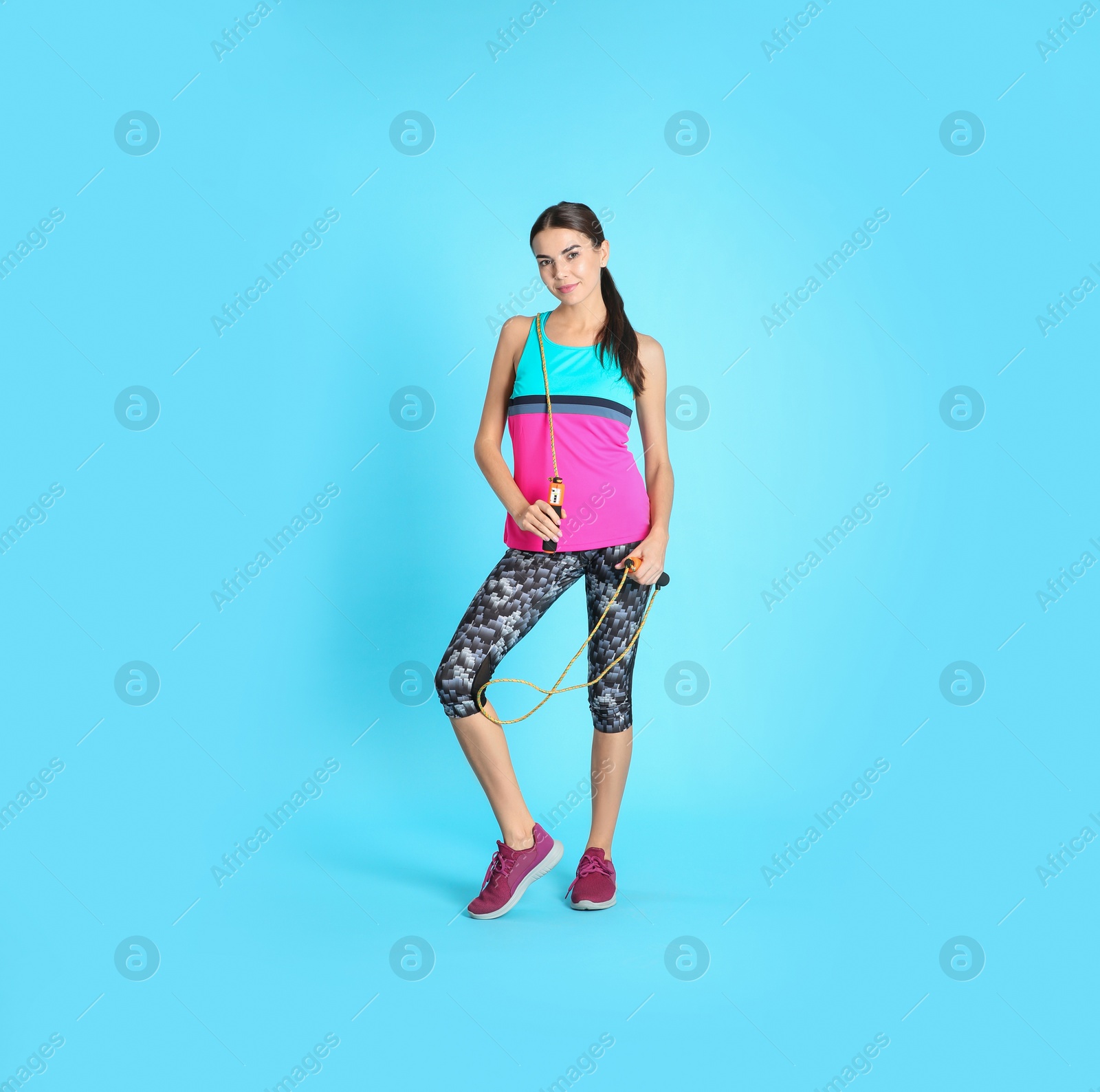 Photo of Full length portrait of young sportive woman with jump rope on color background