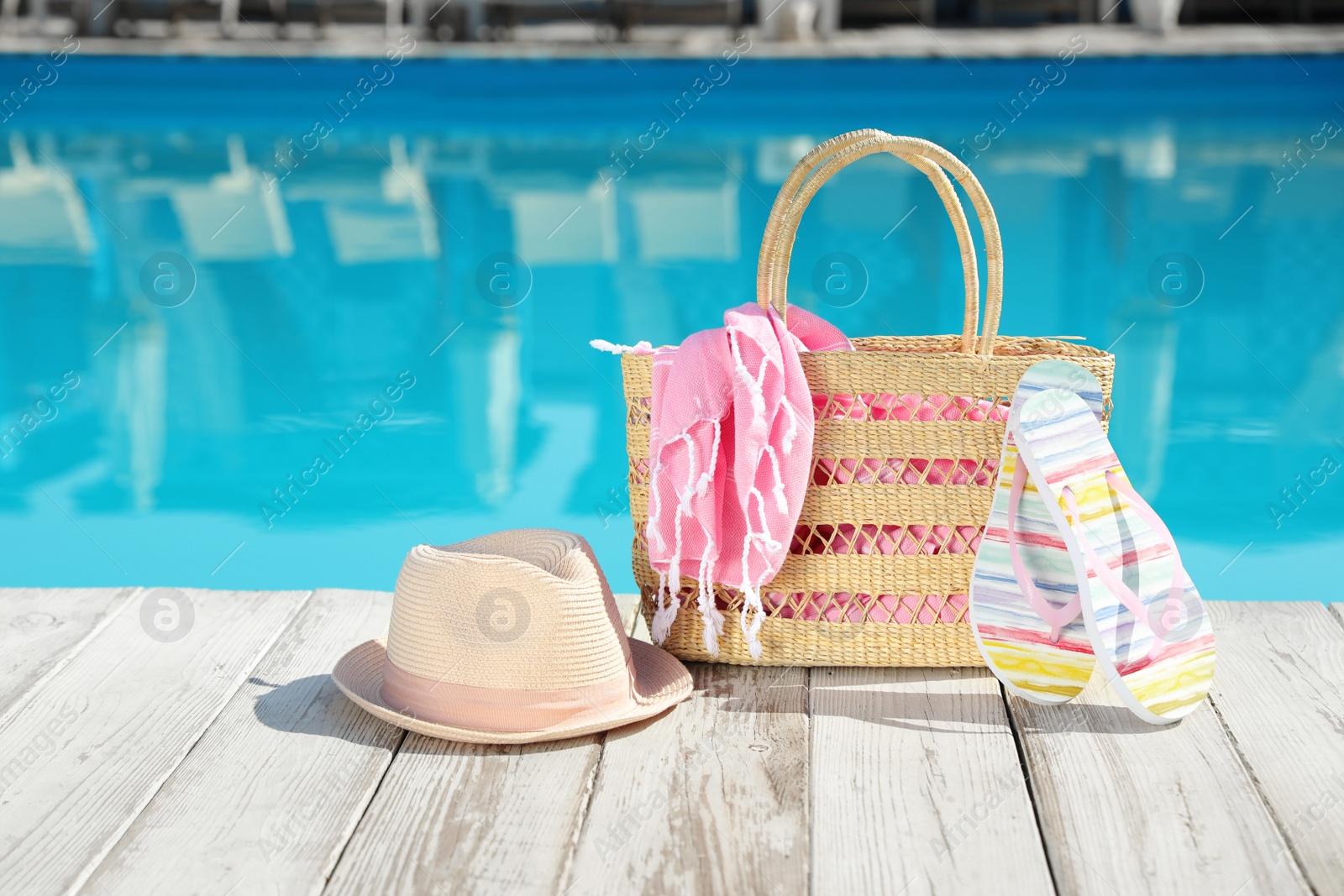 Photo of Beach accessories on wooden deck near outdoor swimming pool