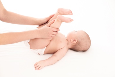 Photo of Mother and her cute child on white bed. Baby massage and exercises