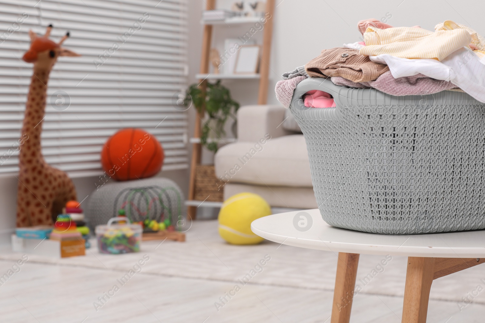 Photo of Laundry basket with baby clothes on white table in room. Space for text