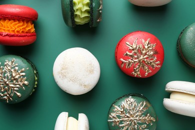 Beautifully decorated Christmas macarons on green background, flat lay
