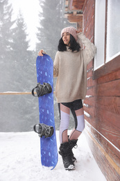 Photo of Young woman with snowboard wearing winter sport clothes outdoors