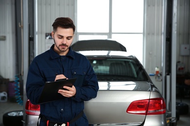 Photo of Portrait of technician with clipboard at automobile repair shop