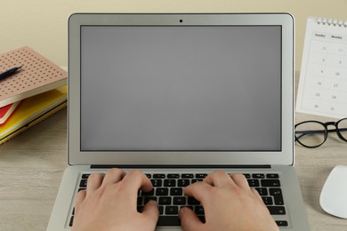 Woman using laptop for online studying at wooden table, closeup. Distance learning