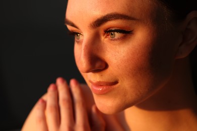 Fashionable portrait of beautiful woman with fake freckles on dark background, closeup