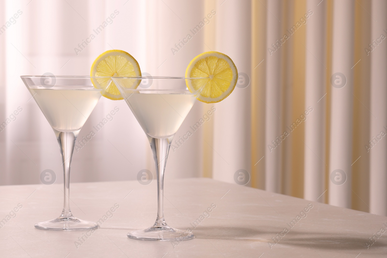 Photo of Elegant martini glasses with fresh cocktail and lemon slices on white table indoors. Space for text