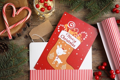 Photo of Flat lay composition with Christmas card and festive  decor on wooden background