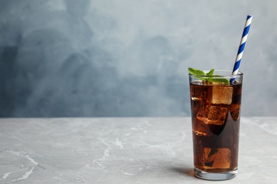 Photo of Refreshing soda drink with straw on grey table against blue background, space for text