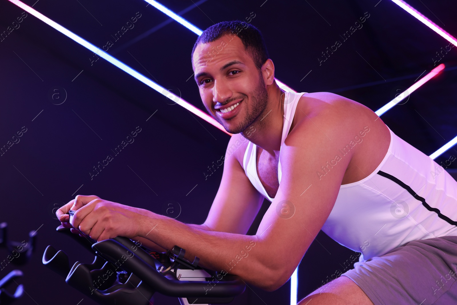 Photo of Young man training on exercise bike in fitness club