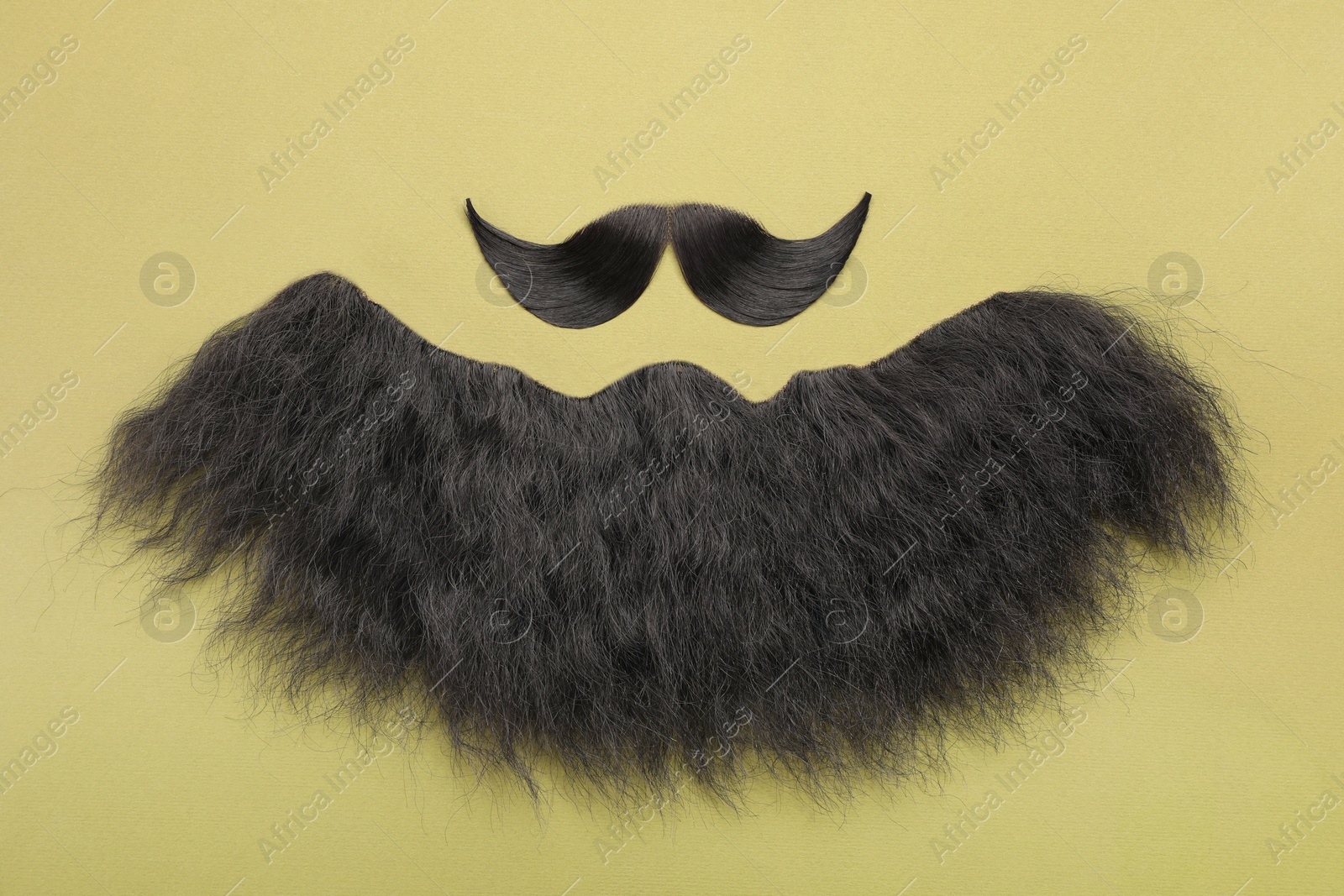 Photo of Artificial moustache and beard on khaki background, top view