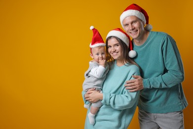 Happy couple with cute baby wearing Santa hats on yellow background, space for text. Christmas season