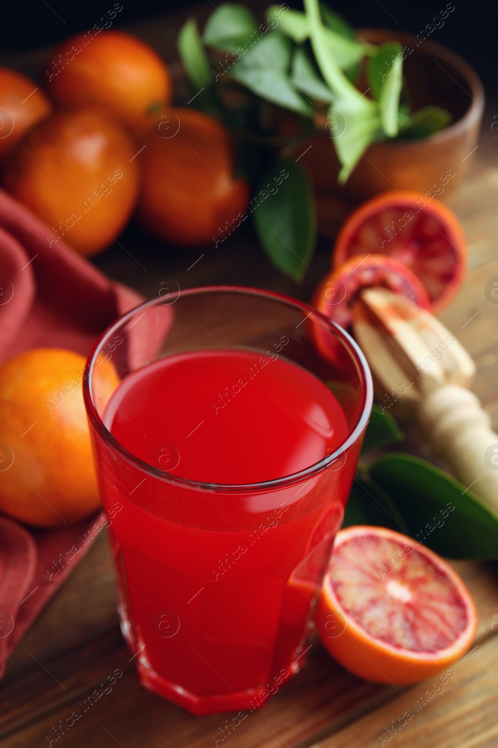 Photo of Tasty sicilian orange juice in glass and fruits on wooden table