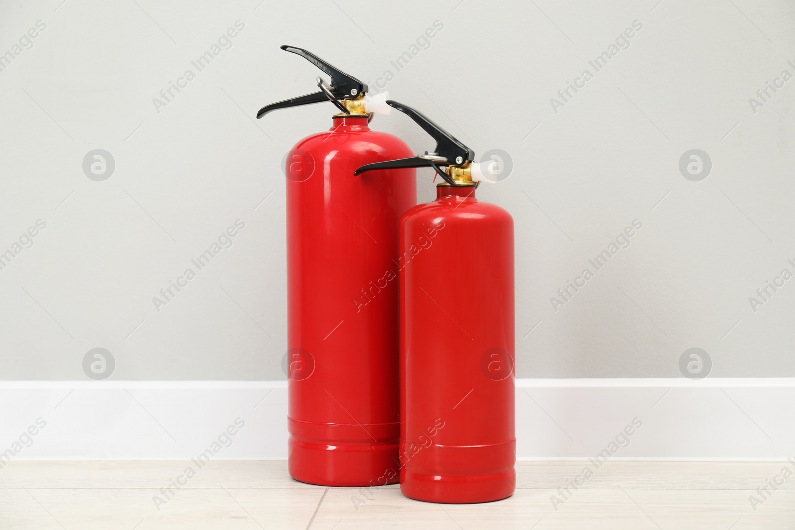 Photo of Fire extinguishers on floor near light grey wall