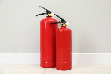 Photo of Fire extinguishers on floor near light grey wall