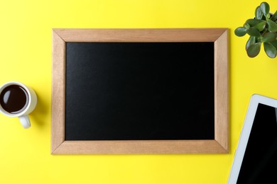 Photo of Clean small chalkboard, coffee, plant and tablet on yellow background, flat lay