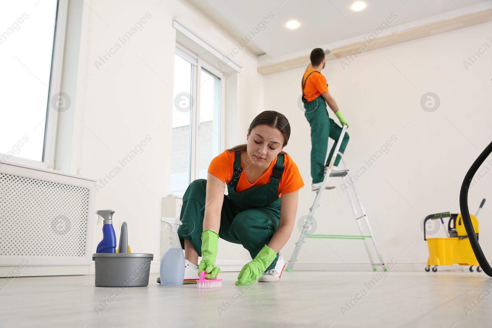 Photo of Professional young janitor polishing floor indoors. Cleaning service