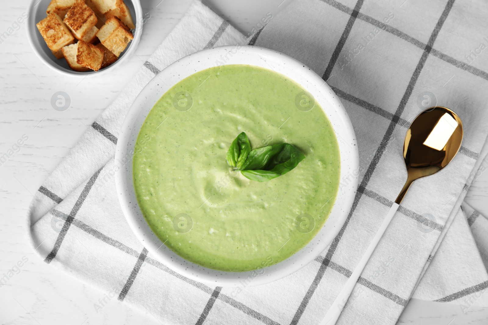 Photo of Delicious broccoli cream soup served on white wooden table, flat lay