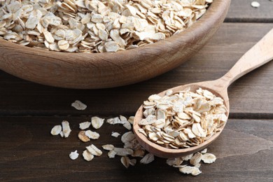 Photo of Bowl and spoon with oatmeal on wooden table, closeup