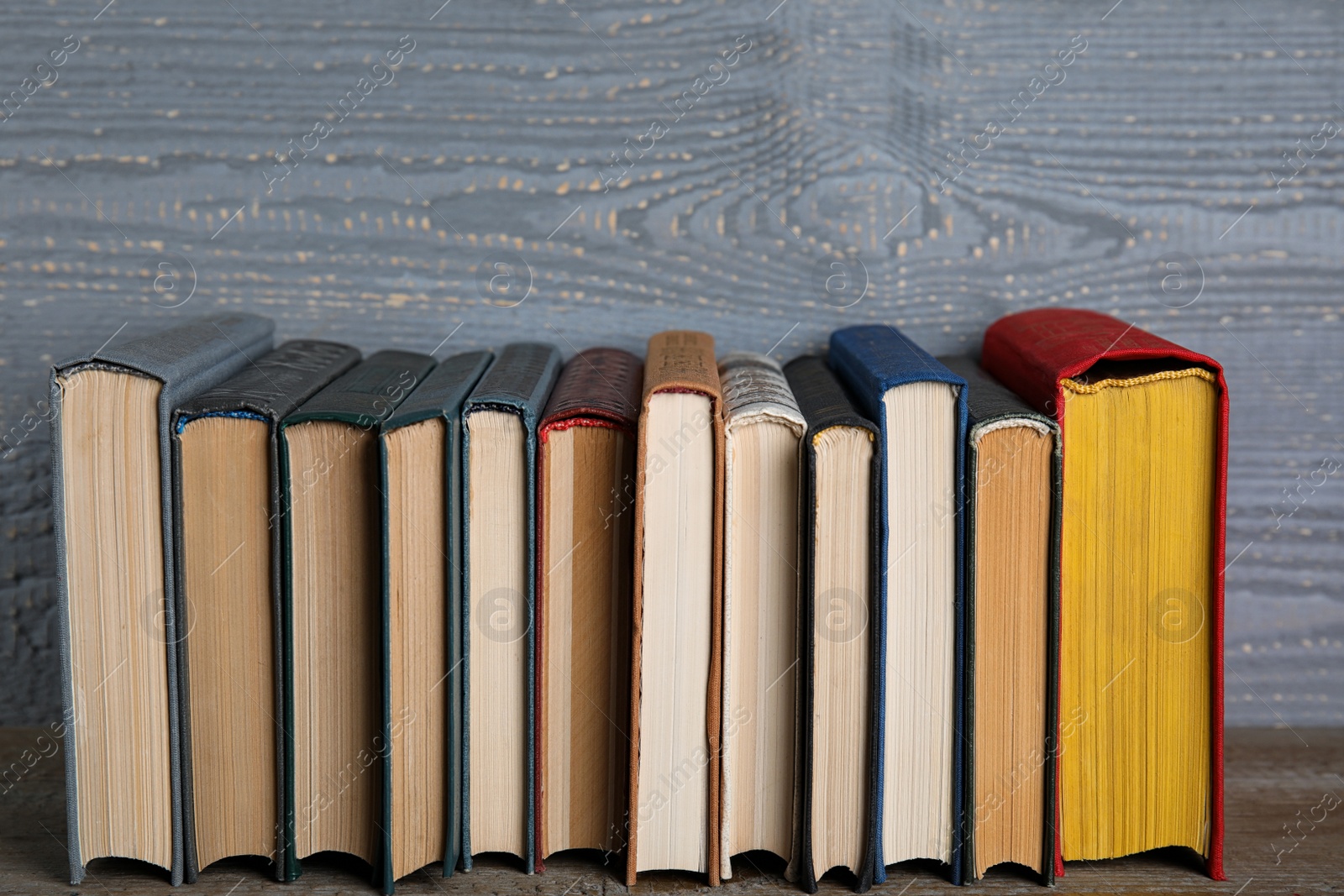 Photo of Stack of hardcover books on wooden table against grey background