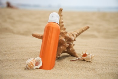 Photo of Sunscreen, starfish and seashells on beach. Sun protection care