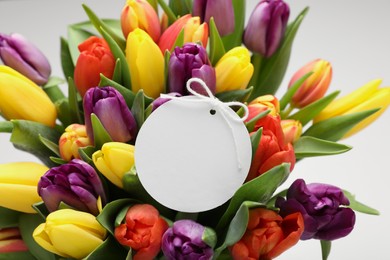 Photo of Bouquet of colorful tulips with blank card on white background, closeup