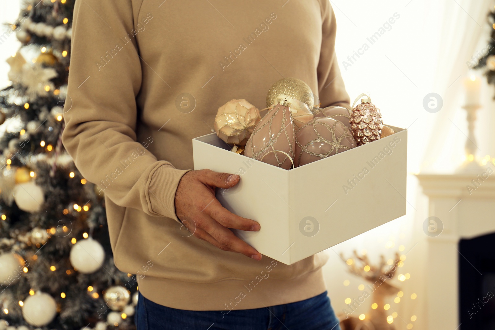 Photo of Man with box of Christmas baubles at home, closeup