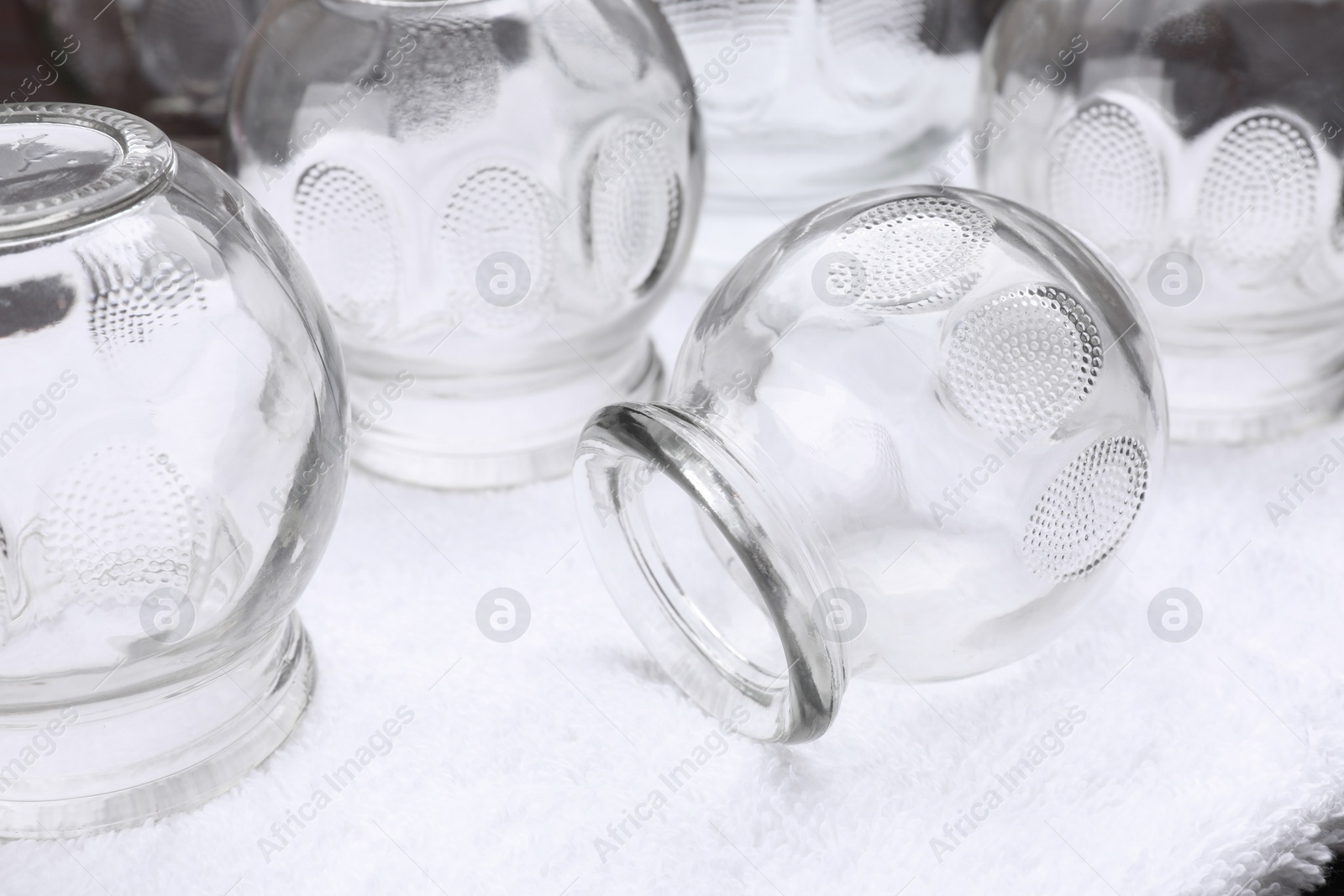Photo of Glass cups on white towel, closeup. Cupping therapy