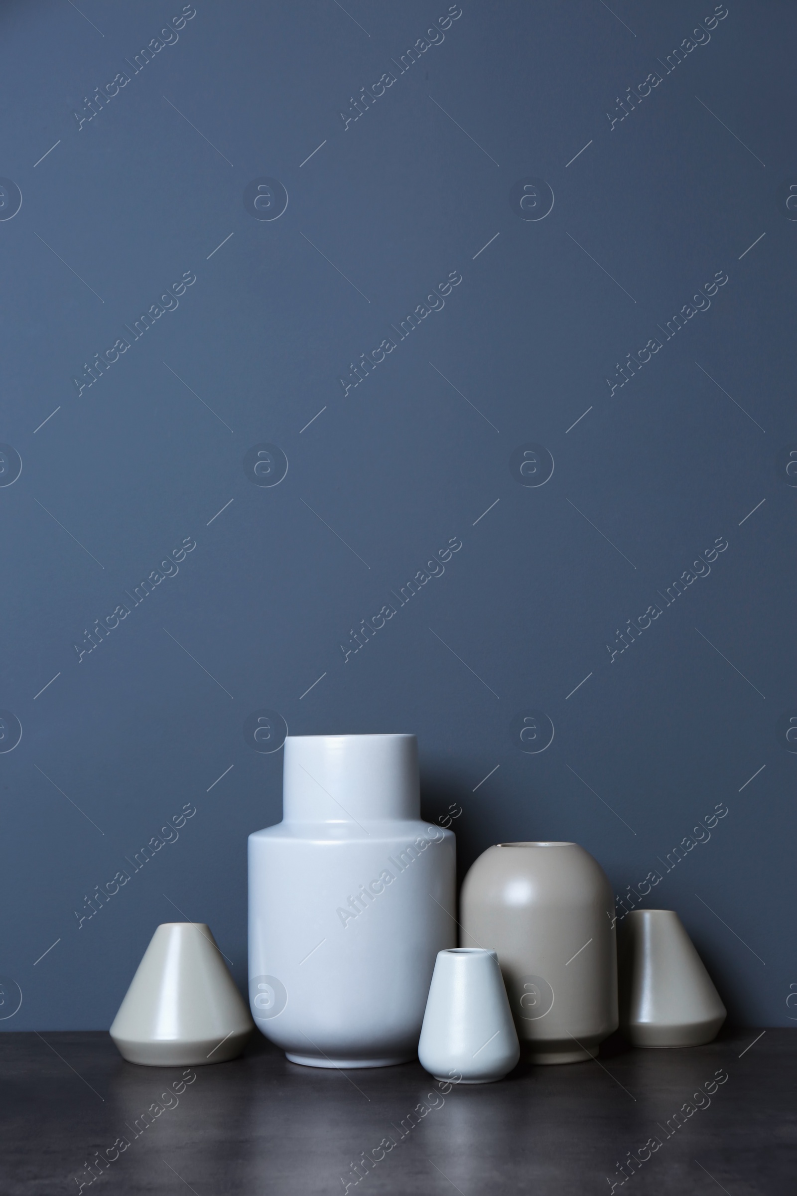 Photo of Beautiful ceramic vases on table against color wall