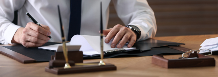 Image of Male notary working at table in office, closeup. Banner design