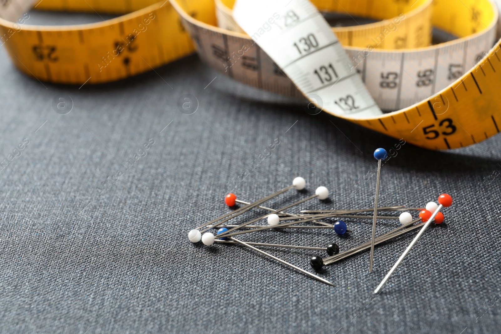 Photo of Pile of pins on fabric, closeup. Tailoring equipment